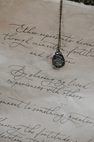 silver talisman amulet necklace on calligraphy poem page