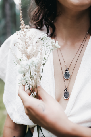 silver coin medallion talisman layering necklaces on woman holding flowers