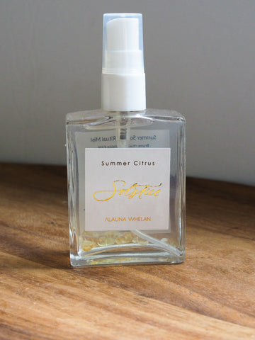 crystal infused body mist with gold foil and white label on wooden tray with white background