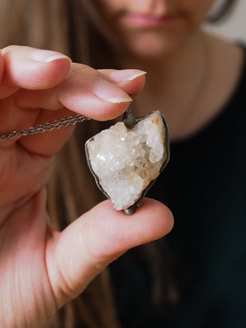woman holding heart shaped raw white quartz healing crystal talisman necklace