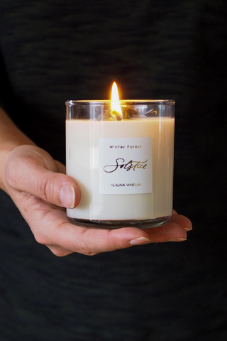 hand holding lit winter solstice soy intention candle