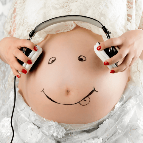 a woman putting a headphone on her belly