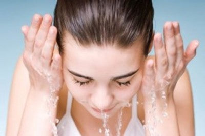 Closeup photo of woman splashing water onto her face