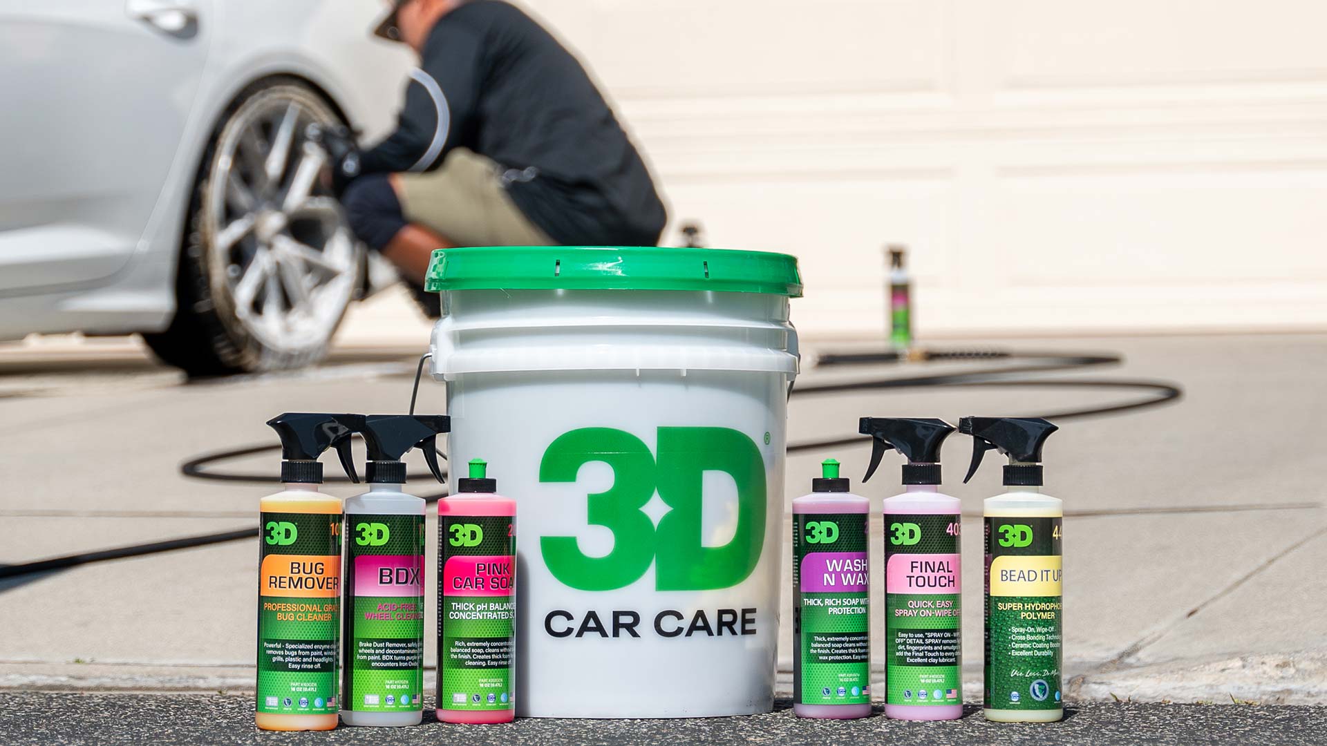 3d car care producuts with detailer washing wheels in background