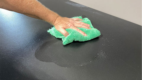 wiping table clean with microfiber towel and cleaner 