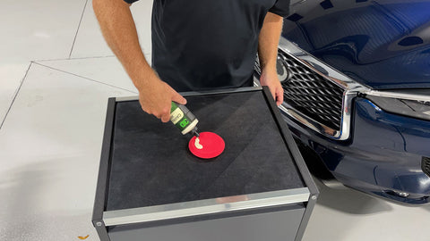 pouring car wax onto a red wax sponge 