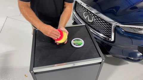 applying car wax to red waxing sponge 