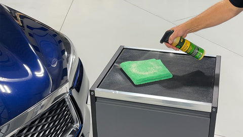 spraying car wax onto a microfiber towel 