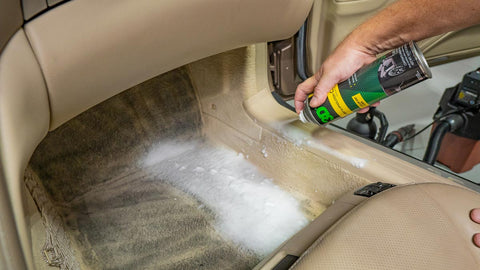 spraying foaming cleaner on car floor 