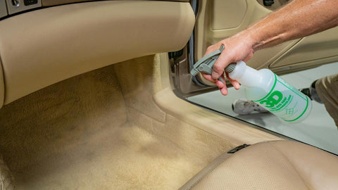 spraying car carpet with cleaner