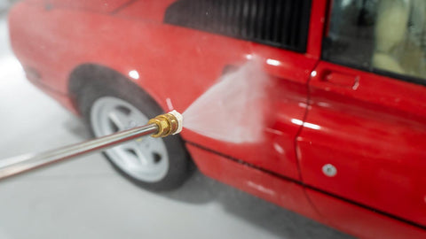 spraying water on car with power washer 