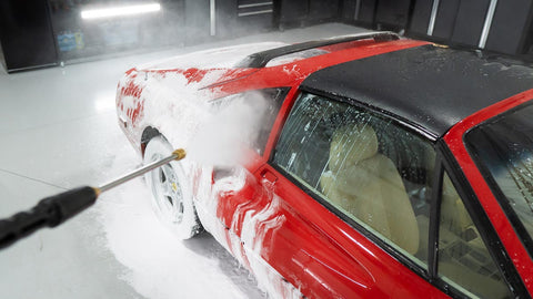 spraying foam off car with water 