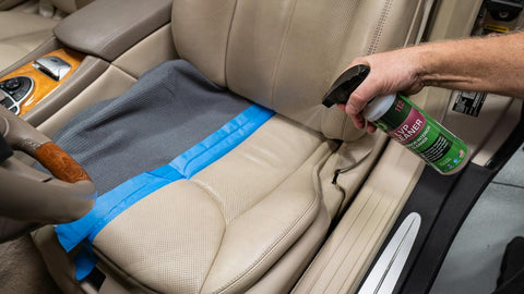 spraying car seat with leather cleaner 