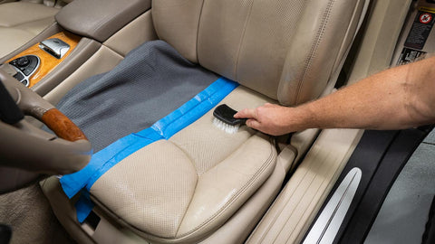 agitating leather car seat with cleaner and a brush 