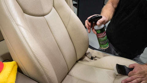 spraying cleaner on leather car seat