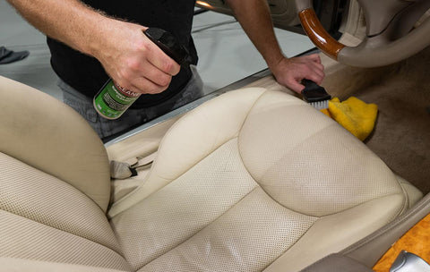 spraying car seat with leather cleaner 