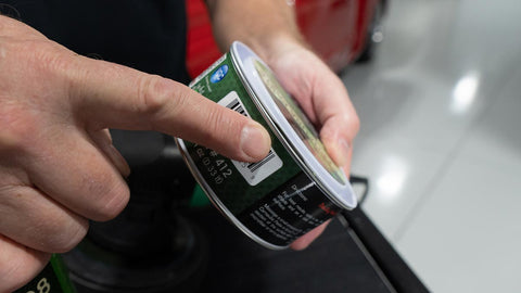 can of car wax with finger pointing to slot on the lid