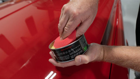 using sponge to pick up car wax from can 