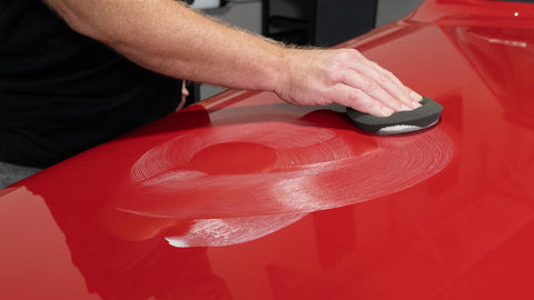 buffing wax into the surface of a car 