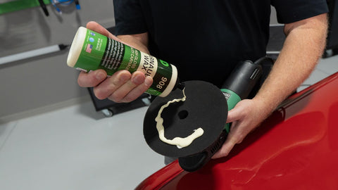 applying liquid car wax to a sponge on a rotary polisher 