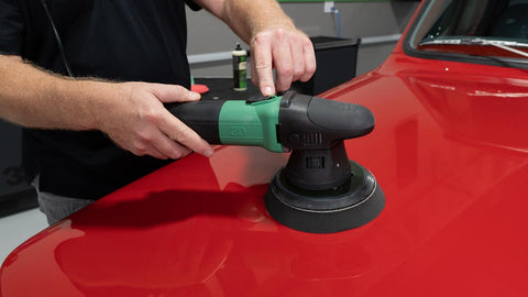 buffing wax onto surface of a car with a rotary polisher 