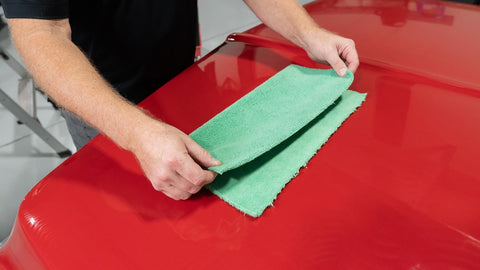 folding a microfiber towel on the surface of a car 