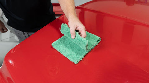 folding a microfiber towel on the surface of a car 