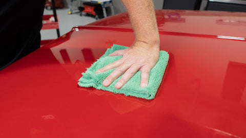 wiping surface of a car with a microfiber towel 