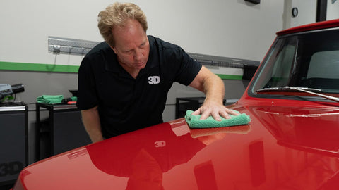 wiping wax off the surface of a car 