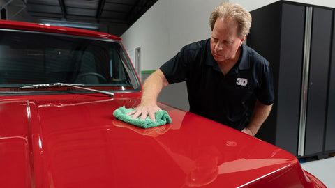 wiping wax off the surface of a car 