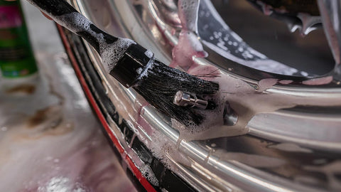 scrubbing car rims with a soapy brush