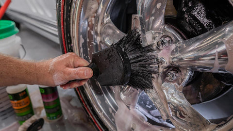 scrubbing tire rims with a soapy scrub brush