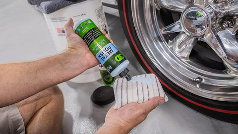 pouring metal polish on a rag before polishing car rims