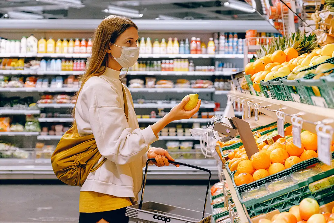 Woman with a mask shopping at the fruit counter