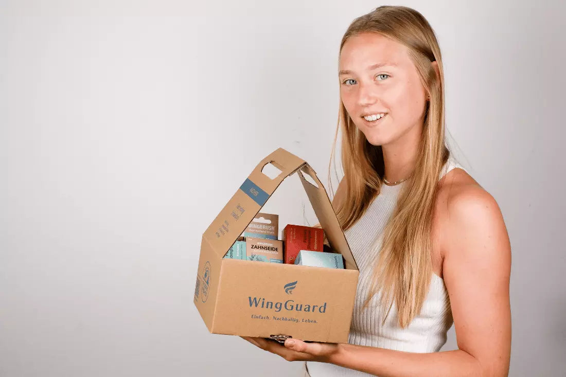 Manufacturer to Customer - junge Frau präsentiert wiederverwendbaren Versandkarton mit nachhaltigen und natürlichen Produkten direkt vom Händler