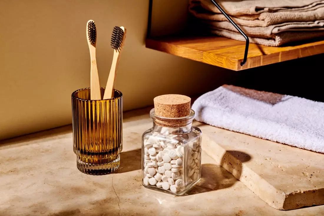 Bamboo toothbrushes and toothpaste tablets in glass