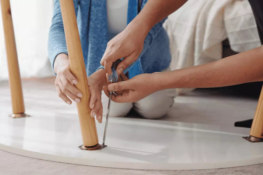 Two people are repairing a table leg