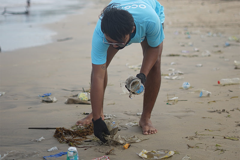 Mann sammelt Müll an Strand