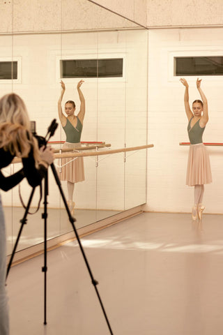 ballet photoshoot behind the scenes with ballerina wearing a green ballet leotard, pink ballet skirt and point shoes