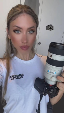 bella Turolla wearing her imperfect pointes white logo tee shirt and handling a very expensive camera