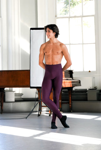 A male ballet dancer wearing a pair of men's rehearsal ballet tights in the middle of a dnace studio