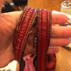 Photo of leather strap with fraying stitching and material.