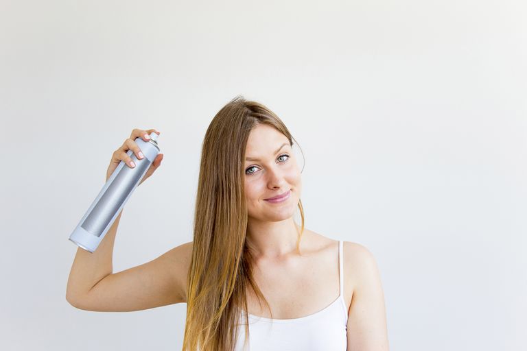 woman spraying her hair.