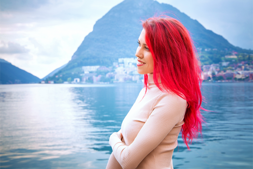 women with red colored hair standing in front of a lake