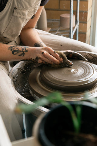 A close up shot of a large pot being made on the potters wheel. The clay is rich and dark, and is unrefined native clay from Bunurong land.