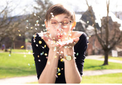 Junge Frau pustet Saatgutkonfetti aus den Händen