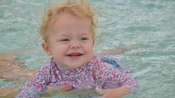 Isabelle smiling in the water learning to kick 