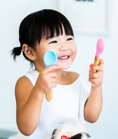 child with pink and blue spoon