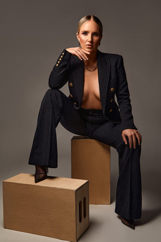 Brandi Gregge wearing a black suit while sitting on a wooden box.