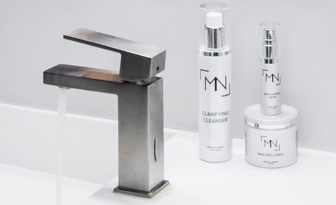 Photo of a sink faucet next to three M&N skincare products.